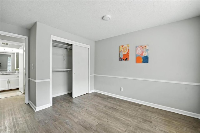 12704 W 110th Ter, Overland Park, KS 66210 - unfurnished bedroom with wood finished floors, a textured ceiling, and a closet