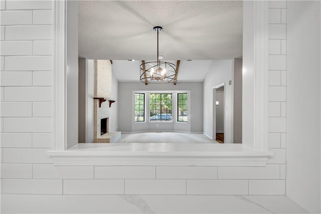 11016 W 96th Ter, Overland Park, KS 66214 - unfurnished living room featuring a textured ceiling, a chandelier, and a large fireplace