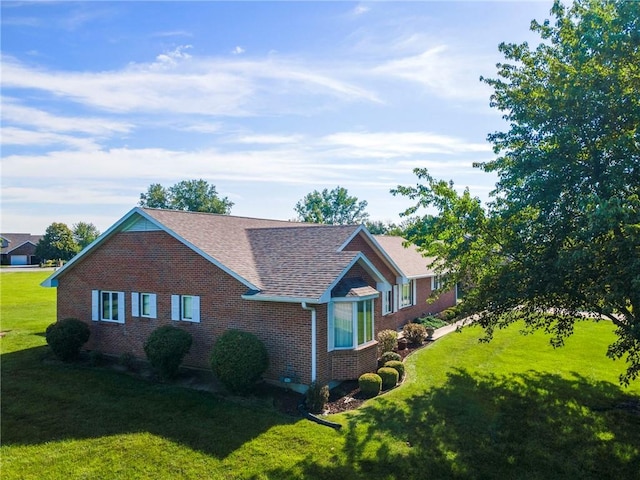 205 E 10th St, Carrollton, MO 64633 - view of home's exterior with brick siding, a lawn, and roof with shingles