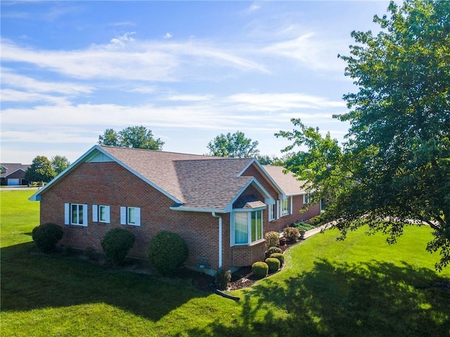 205 E 10th St, Carrollton, MO 64633 - view of home's exterior with brick siding, a yard, and roof with shingles