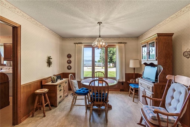 205 E 10th St, Carrollton, MO 64633 - dining space with wainscoting, a chandelier, wallpapered walls, a textured ceiling, and wood walls