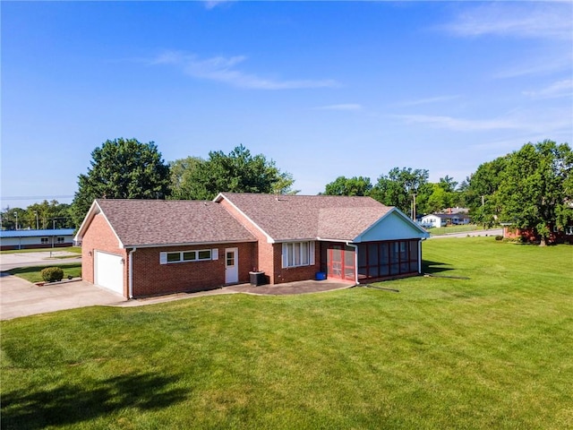 205 E 10th St, Carrollton, MO 64633 - single story home with a front lawn, driveway, brick siding, a sunroom, and an attached garage