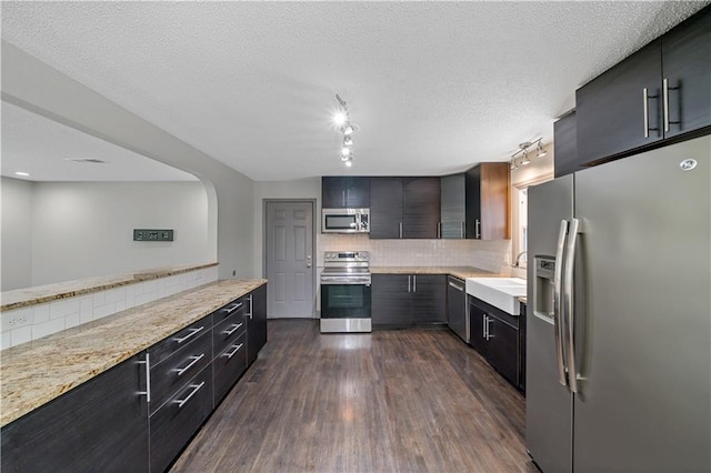 2517 Red Bridge Ter, Kansas City, MO 64131 - kitchen featuring appliances with stainless steel finishes, rail lighting, tasteful backsplash, dark wood-style flooring, and modern cabinets
