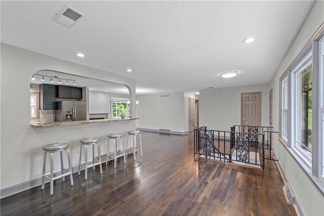 2517 Red Bridge Ter, Kansas City, MO 64131 - kitchen featuring stainless steel refrigerator with ice dispenser, dark wood-style floors, a breakfast bar, a textured ceiling, and tasteful backsplash