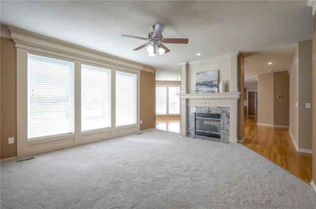 12337 Gillette St, Overland Park, KS 66213 - unfurnished living room with carpet floors, a ceiling fan, a premium fireplace, a textured ceiling, and ornamental molding