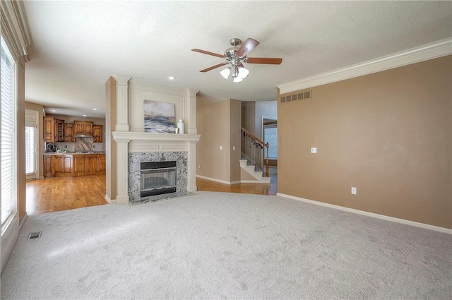 12337 Gillette St, Overland Park, KS 66213 - unfurnished living room with light carpet, a ceiling fan, a fireplace, stairway, and ornamental molding