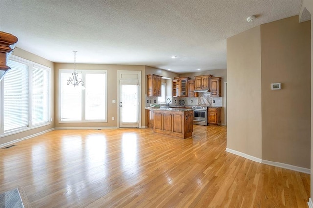 12337 Gillette St, Overland Park, KS 66213 - kitchen with stainless steel range oven, brown cabinetry, a peninsula, a chandelier, and light wood-style floors