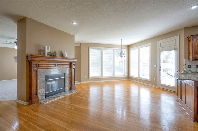 12337 Gillette St, Overland Park, KS 66213 - unfurnished living room with a high end fireplace, light wood finished floors, a textured ceiling, ceiling fan, and recessed lighting