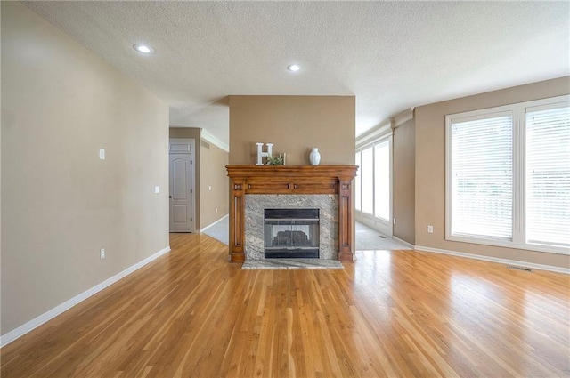 12337 Gillette St, Overland Park, KS 66213 - unfurnished living room with light wood-type flooring, a textured ceiling, a fireplace, and recessed lighting