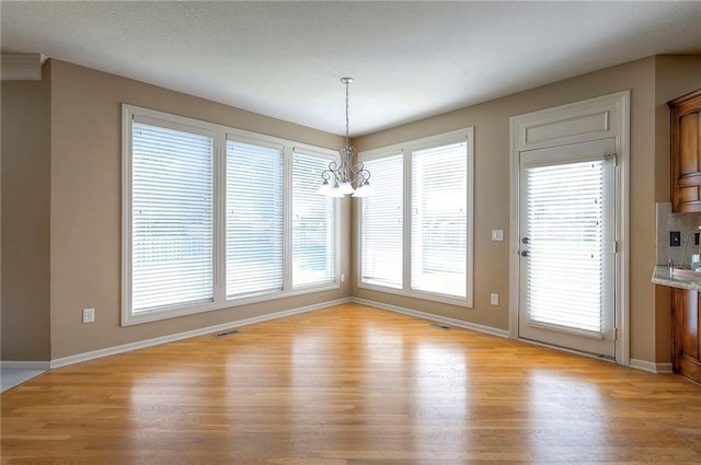 12337 Gillette St, Overland Park, KS 66213 - unfurnished dining area featuring light wood-style floors and a chandelier