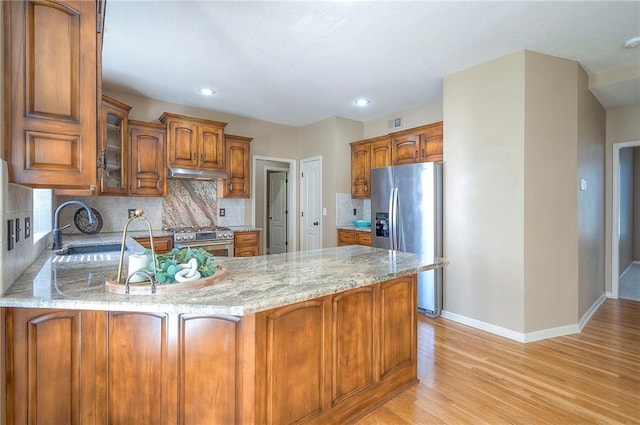 12337 Gillette St, Overland Park, KS 66213 - kitchen with appliances with stainless steel finishes, under cabinet range hood, a peninsula, light wood-type flooring, and light stone countertops