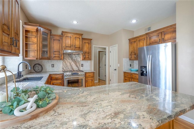 12337 Gillette St, Overland Park, KS 66213 - kitchen with stainless steel appliances, under cabinet range hood, a peninsula, brown cabinetry, and recessed lighting