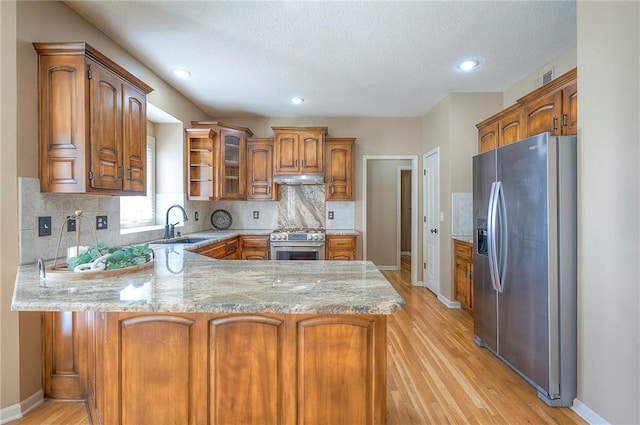 12337 Gillette St, Overland Park, KS 66213 - kitchen featuring stainless steel appliances, a peninsula, light wood-type flooring, brown cabinetry, and decorative backsplash