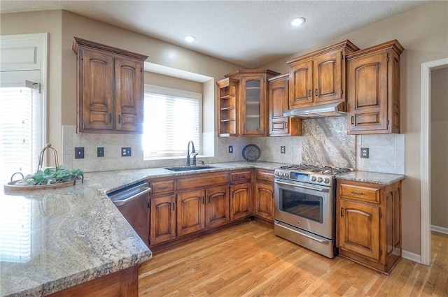 12337 Gillette St, Overland Park, KS 66213 - kitchen with appliances with stainless steel finishes, brown cabinetry, under cabinet range hood, light wood finished floors, and light stone countertops