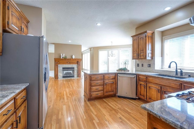 12337 Gillette St, Overland Park, KS 66213 - kitchen with appliances with stainless steel finishes, a peninsula, brown cabinetry, light wood-style floors, and recessed lighting