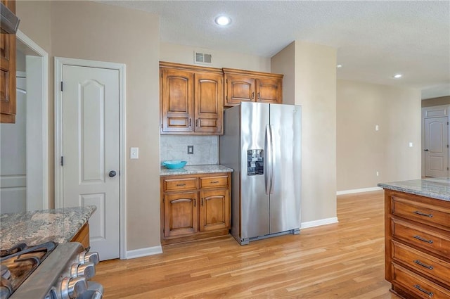 12337 Gillette St, Overland Park, KS 66213 - kitchen with stainless steel fridge, brown cabinets, light wood-type flooring, light stone countertops, and recessed lighting
