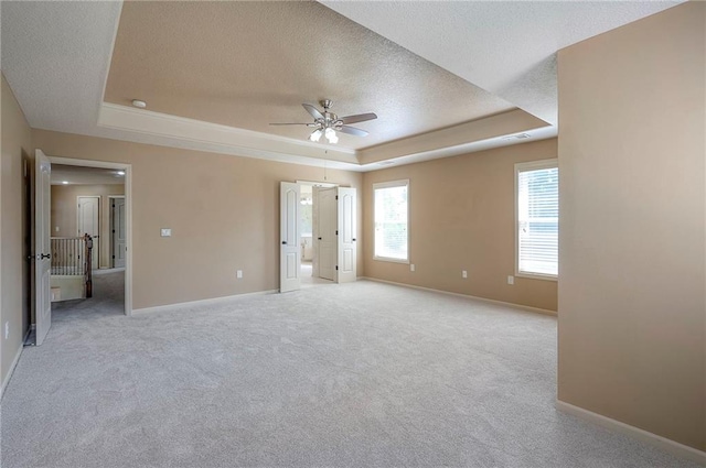 12337 Gillette St, Overland Park, KS 66213 - unfurnished bedroom featuring a tray ceiling, a textured ceiling, light colored carpet, ceiling fan, and ensuite bath