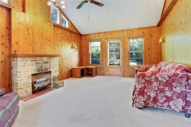 600 W Elm St, Olathe, KS 66061 - carpeted living area featuring vaulted ceiling, wooden walls, plenty of natural light, ceiling fan, and a fireplace