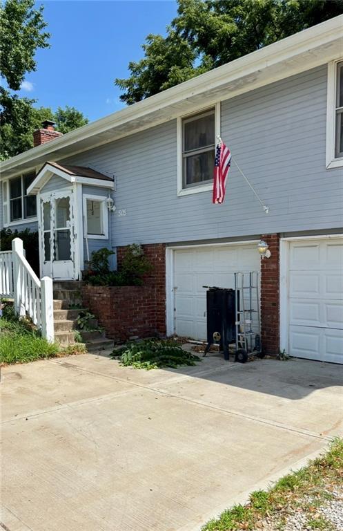 505 E Harold St, Olathe, KS 66061 - view of front of house with an attached garage, brick siding, a chimney, and driveway