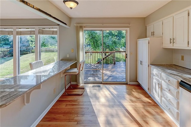 6236 W 156th St, Overland Park, KS 66223 - kitchen featuring stainless steel dishwasher, white cabinets, light stone counters, light wood finished floors, and backsplash