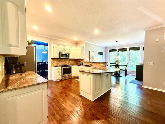 4531 Anderson St, Shawnee, KS 66226 - kitchen featuring crown molding, appliances with stainless steel finishes, decorative backsplash, dark wood-type flooring, and a peninsula