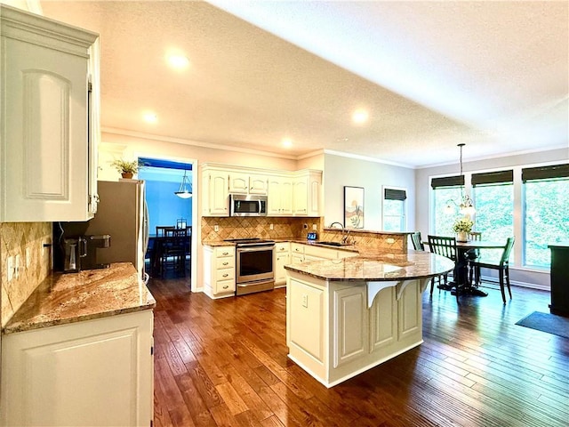4531 Anderson St, Shawnee, KS 66226 - kitchen featuring a peninsula, a breakfast bar area, crown molding, appliances with stainless steel finishes, and backsplash