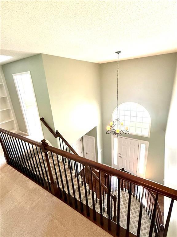 4531 Anderson St, Shawnee, KS 66226 - stairway featuring carpet floors, a chandelier, and a textured ceiling