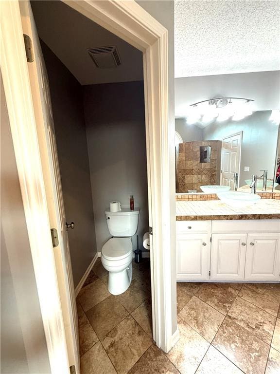 4531 Anderson St, Shawnee, KS 66226 - bathroom featuring vanity, tiled shower, a textured ceiling, and tile patterned flooring