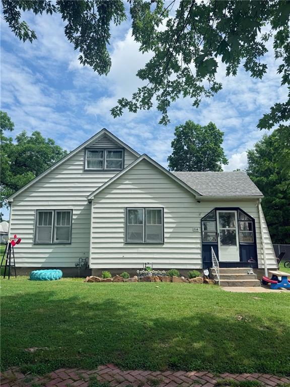 704 W 2nd St, Coffeyville, KS 67337 - bungalow-style house featuring entry steps, a front lawn, and roof with shingles