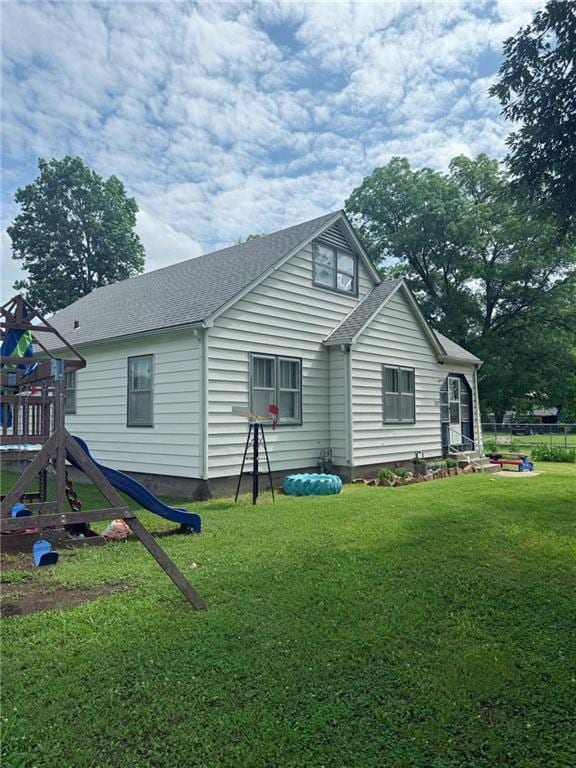 704 W 2nd St, Coffeyville, KS 67337 - rear view of property with a playground, a yard, and a shingled roof