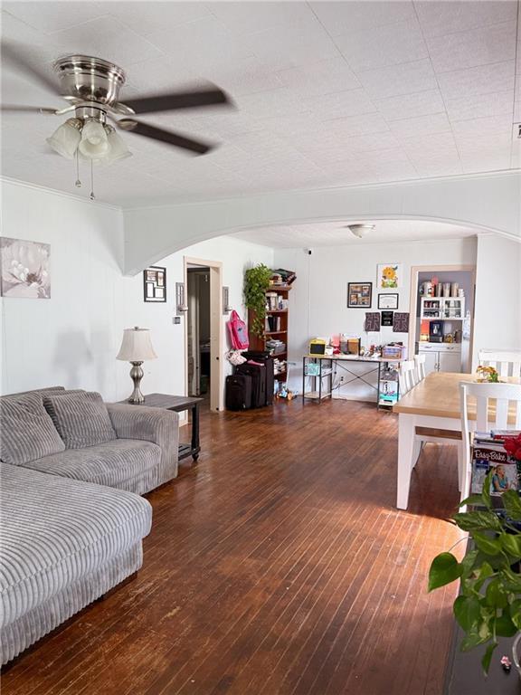 704 W 2nd St, Coffeyville, KS 67337 - living area with arched walkways, wood-type flooring, and a ceiling fan
