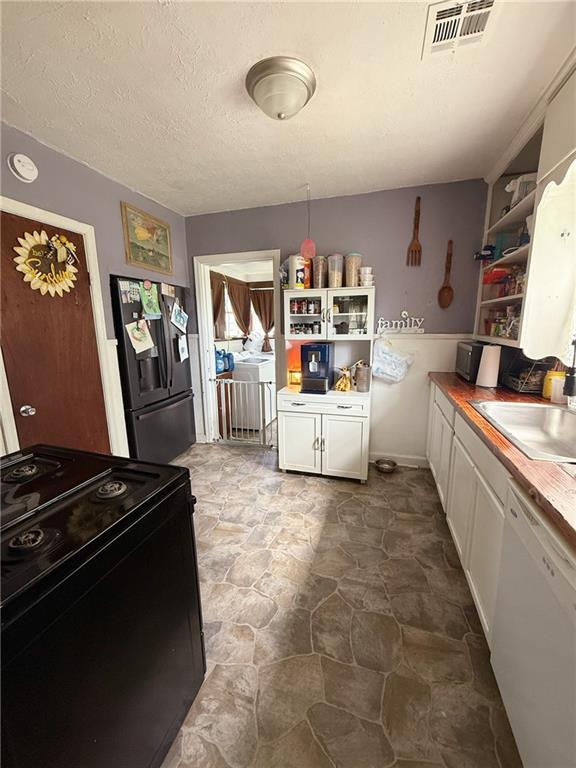 704 W 2nd St, Coffeyville, KS 67337 - kitchen with black appliances, open shelves, white cabinetry, stone finish flooring, and a textured ceiling