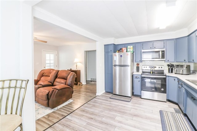 516 W 7th St, Carrollton, MO 64633 - kitchen with stainless steel appliances, blue cabinetry, light countertops, and open floor plan