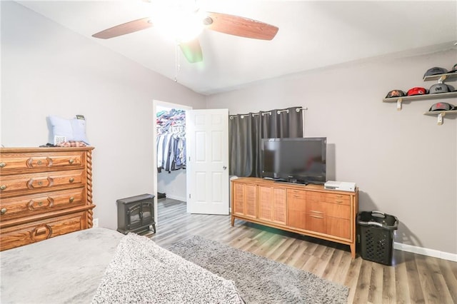 516 W 7th St, Carrollton, MO 64633 - bedroom featuring a wood stove, light wood finished floors, lofted ceiling, a spacious closet, and ceiling fan