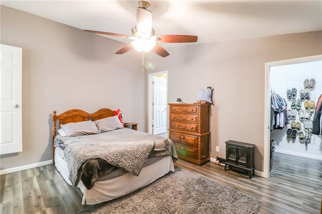 516 W 7th St, Carrollton, MO 64633 - bedroom featuring a wood stove, wood finished floors, a walk in closet, a closet, and ceiling fan
