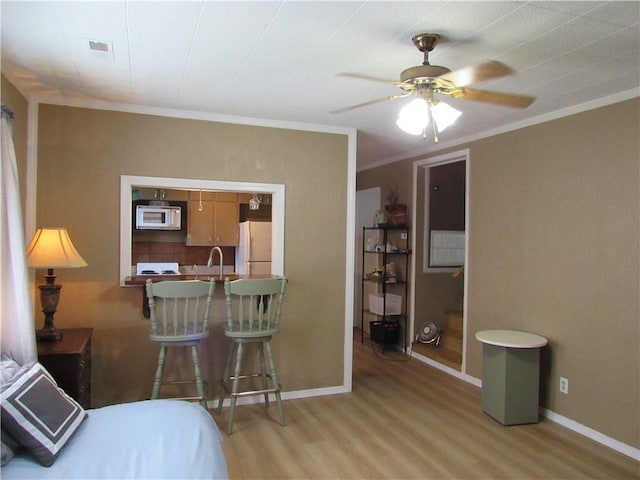 706 W 10th St, Sedalia, MO 65301 - bedroom with freestanding refrigerator, light wood finished floors, ornamental molding, and ceiling fan