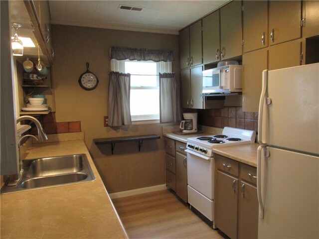 706 W 10th St, Sedalia, MO 65301 - kitchen with white appliances, light wood-style flooring, tasteful backsplash, light countertops, and ornamental molding