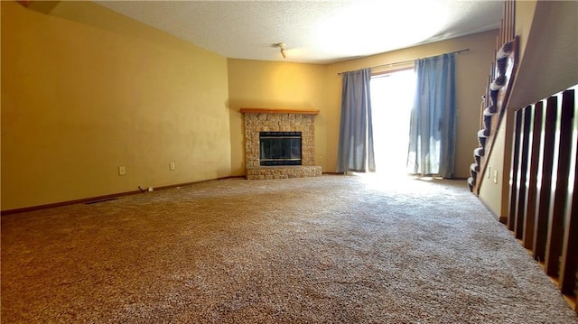 2604 S Peck Ct Unit B, Independence, MO 64055 - unfurnished living room featuring carpet flooring, a glass covered fireplace, and a textured ceiling