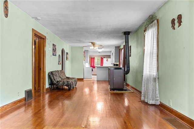 1234 S Pearl St, Independence, MO 64055 - living area with arched walkways, wood finished floors, a ceiling fan, and a wood stove