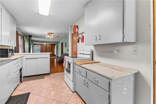 1234 S Pearl St, Independence, MO 64055 - kitchen featuring white electric range, light countertops, light tile patterned floors, and stainless steel microwave
