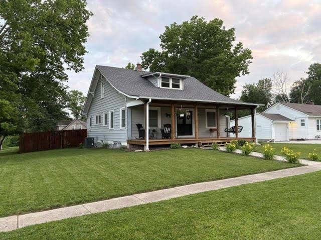 383 E Broadway St, Peculiar, MO 64078 - view of front of home with covered porch, a chimney, a garage, and a shingled roof