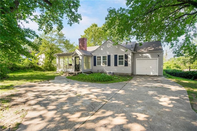 6347 Sni A Bar Rd, Kansas City, MO 64129 - ranch-style house featuring a chimney, an attached garage, concrete driveway, and a sunroom