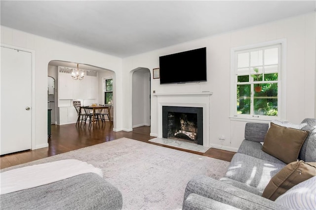 6347 Sni A Bar Rd, Kansas City, MO 64129 - living room featuring arched walkways, wood finished floors, a chandelier, and a fireplace with flush hearth