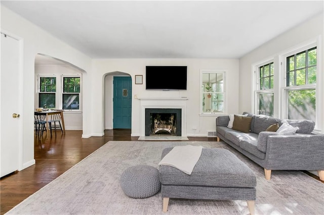 6347 Sni A Bar Rd, Kansas City, MO 64129 - living area featuring arched walkways, dark wood-style flooring, and a fireplace with flush hearth