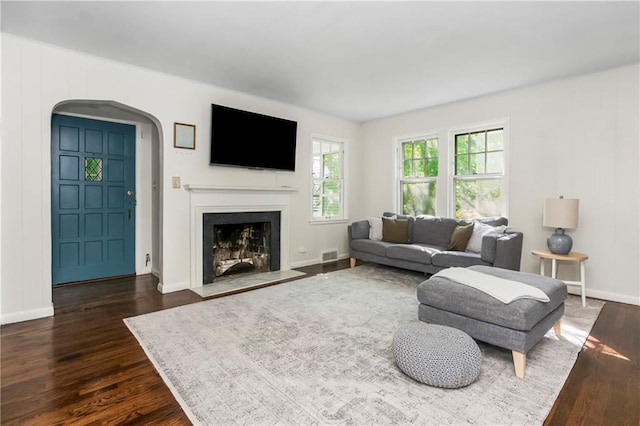 6347 Sni A Bar Rd, Kansas City, MO 64129 - living room with arched walkways, dark wood-type flooring, and a fireplace