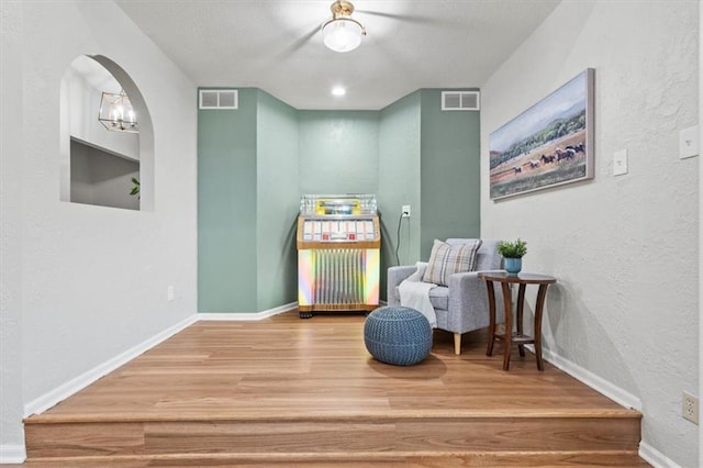 1803 N Jeter Rd, Raymore, MO 64083 - sitting room with wood finished floors, a textured wall, arched walkways, built in shelves, and a chandelier