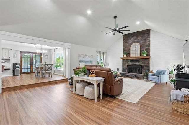 1803 N Jeter Rd, Raymore, MO 64083 - living room featuring a ceiling fan, a brick fireplace, a chandelier, light wood-style flooring, and high vaulted ceiling