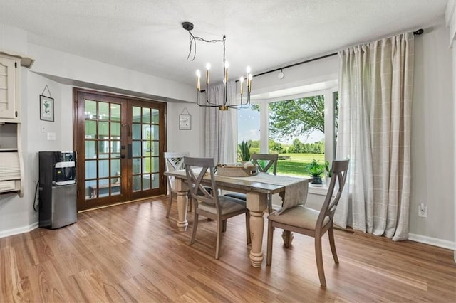 1803 N Jeter Rd, Raymore, MO 64083 - dining room with french doors, a chandelier, light wood-style flooring, and healthy amount of natural light