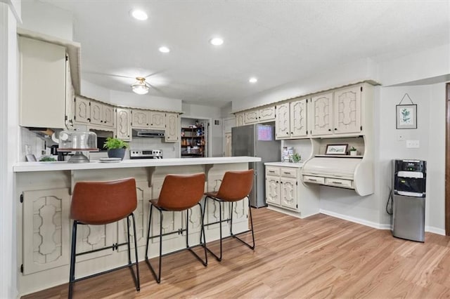 1803 N Jeter Rd, Raymore, MO 64083 - kitchen featuring freestanding refrigerator, a peninsula, exhaust hood, electric range, and a kitchen breakfast bar