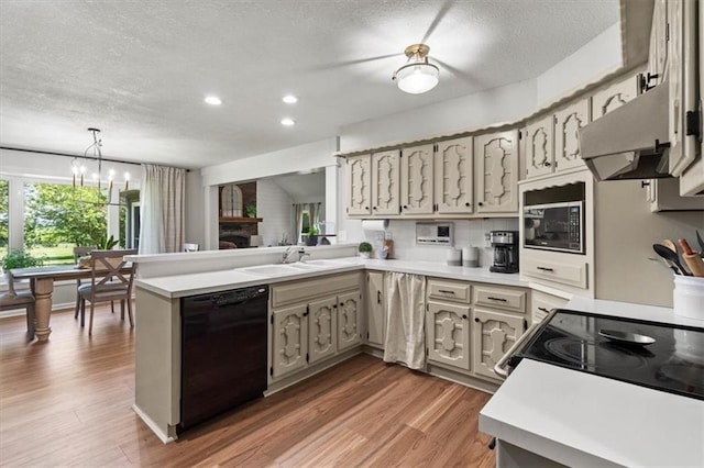 1803 N Jeter Rd, Raymore, MO 64083 - kitchen with dishwasher, extractor fan, a peninsula, a textured ceiling, and wood finished floors